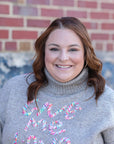 Taupe sweater with give me love stitched in multi color from Favored and Common