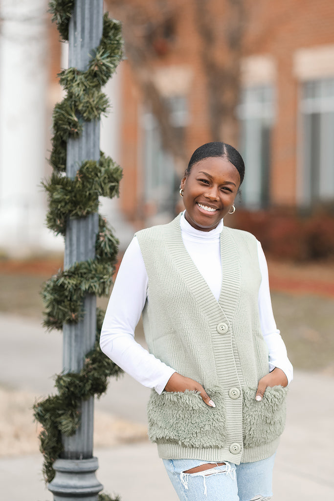 Sage green sweater vest with faux fur front pockets from Favored and Common in NC